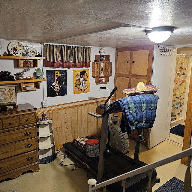 workout area featuring wood walls and a textured ceiling