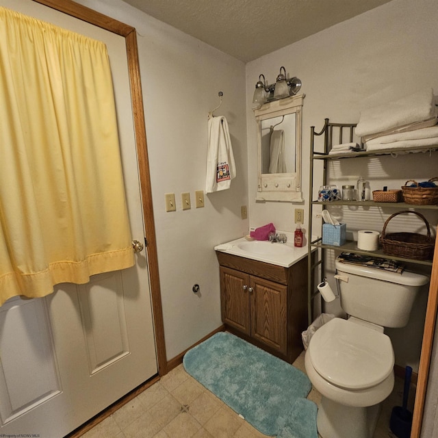 bathroom with vanity, toilet, and a textured ceiling