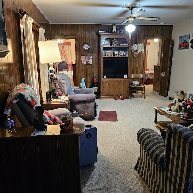 carpeted living room featuring ceiling fan and wood walls