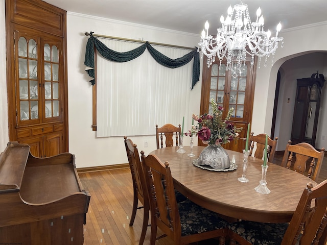 dining area with crown molding, wood-type flooring, and an inviting chandelier