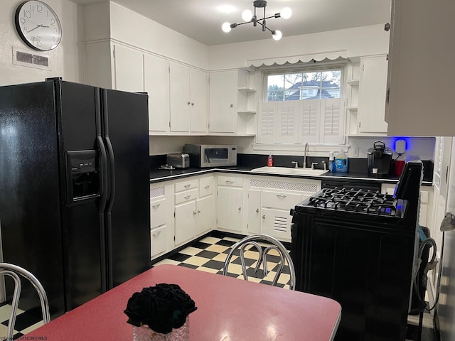 kitchen with black fridge, white cabinetry, and sink