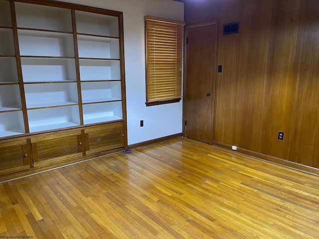 unfurnished room with wooden walls and light wood-type flooring