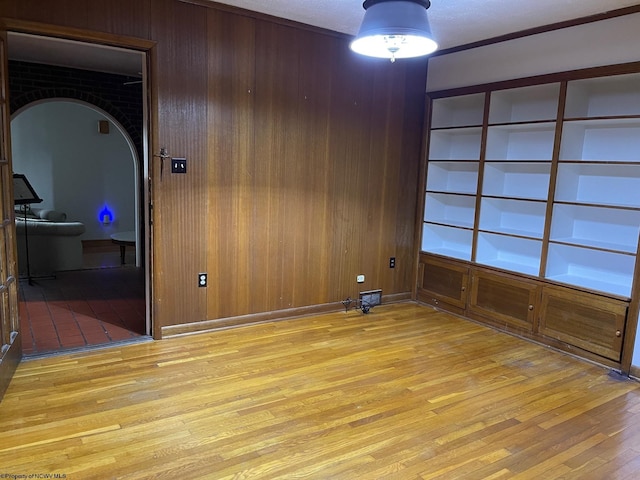 unfurnished room with wood walls and light wood-type flooring