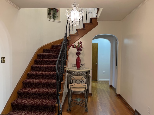 stairway with hardwood / wood-style flooring, an inviting chandelier, and ornamental molding