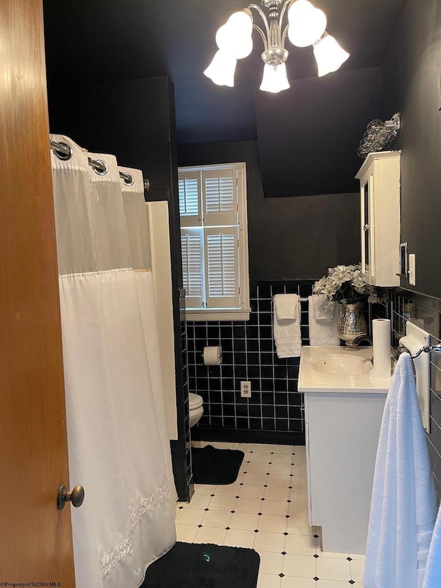 bathroom with vanity, toilet, tile walls, and a notable chandelier