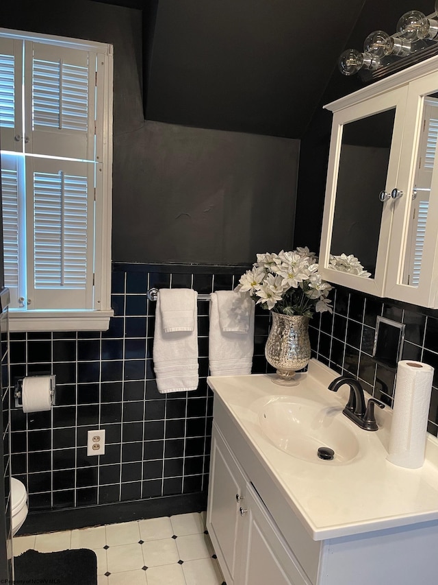 bathroom featuring vanity, toilet, and tile walls