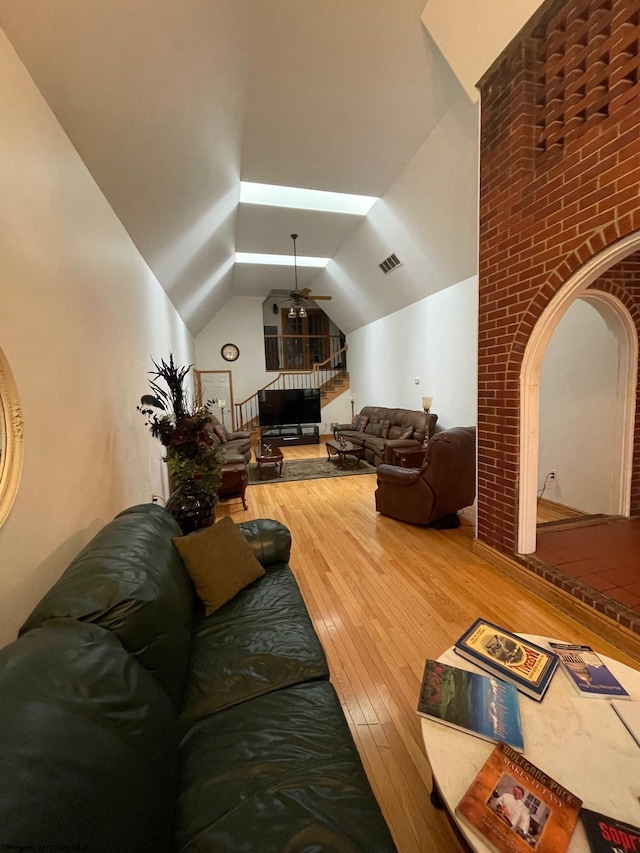 living room with lofted ceiling with skylight, hardwood / wood-style floors, and ceiling fan