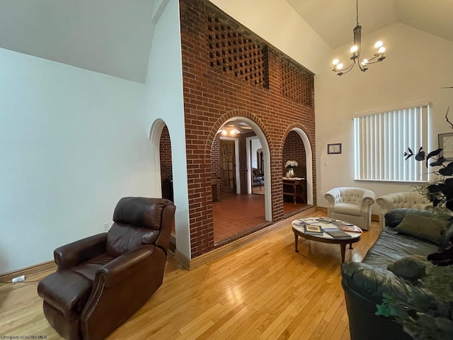 living room featuring a chandelier, light hardwood / wood-style floors, and high vaulted ceiling