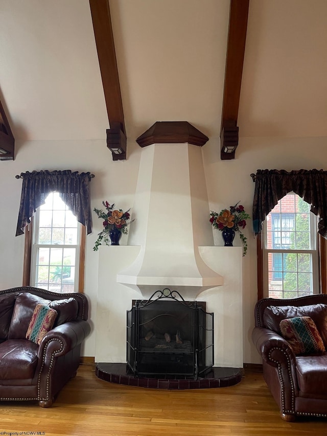 living room featuring a fireplace, beamed ceiling, and hardwood / wood-style flooring