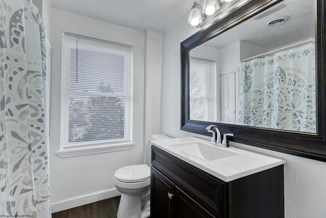 bathroom with a wealth of natural light, toilet, vanity, and hardwood / wood-style flooring