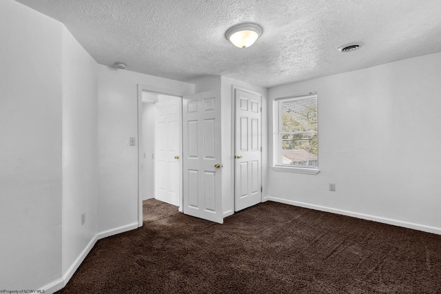 unfurnished bedroom featuring dark colored carpet and a textured ceiling