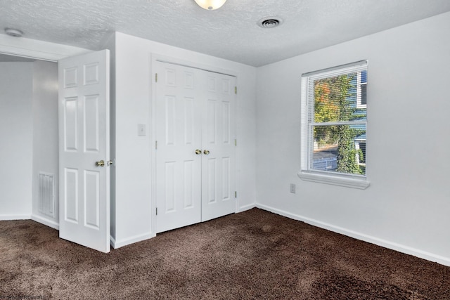 unfurnished bedroom with carpet flooring, a textured ceiling, and a closet