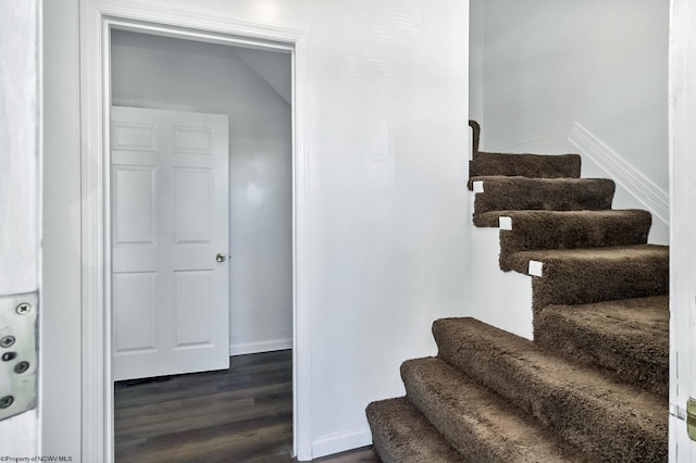 stairway featuring vaulted ceiling and hardwood / wood-style flooring