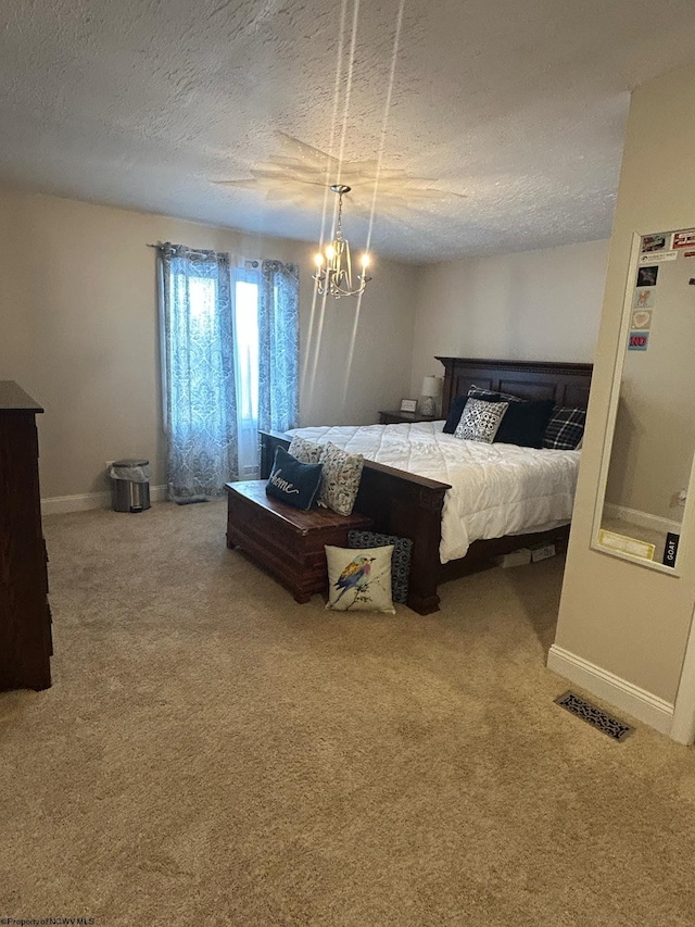 carpeted bedroom featuring a notable chandelier and a textured ceiling