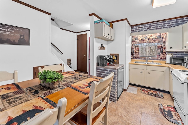 kitchen featuring crown molding, sink, light tile patterned floors, white stove, and white cabinetry