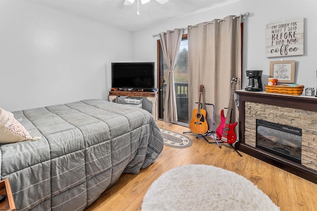 bedroom with ceiling fan, wood-type flooring, a fireplace, and access to outside