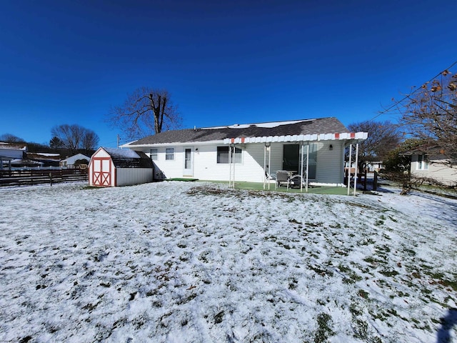 snow covered rear of property with a shed