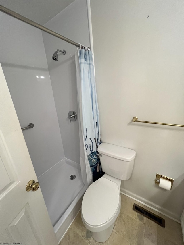 bathroom featuring a shower with curtain and toilet