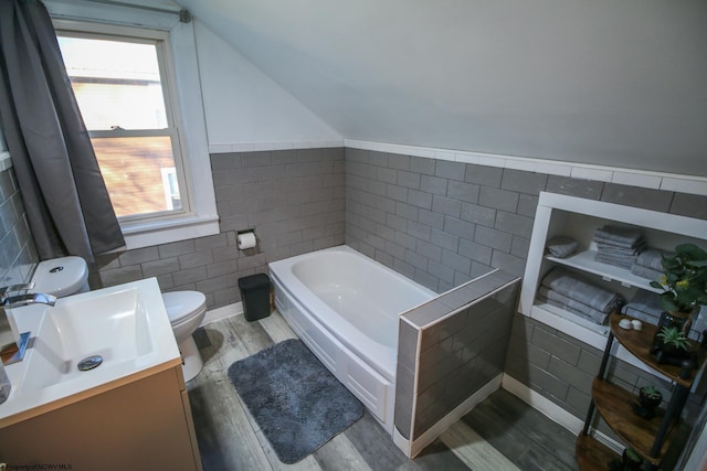 bathroom with lofted ceiling, hardwood / wood-style flooring, toilet, a tub to relax in, and tile walls