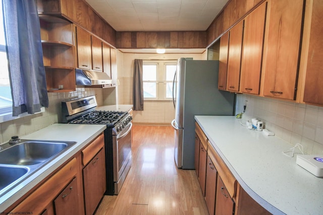 kitchen with tasteful backsplash, sink, stainless steel appliances, and light hardwood / wood-style floors