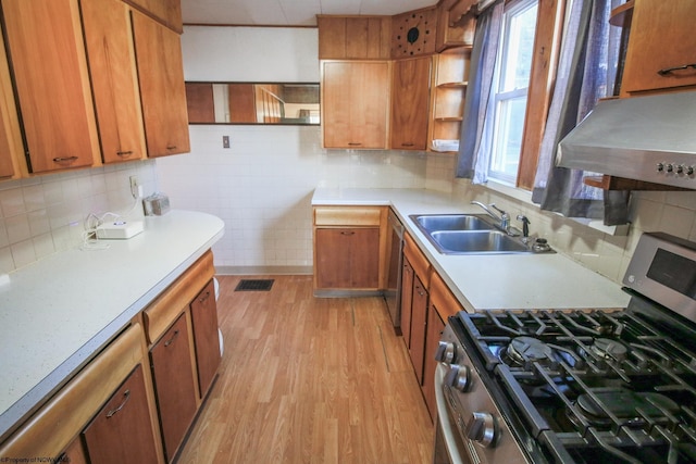 kitchen with decorative backsplash, gas stove, extractor fan, sink, and light hardwood / wood-style floors