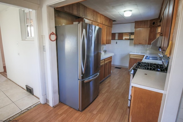 kitchen featuring appliances with stainless steel finishes, light hardwood / wood-style floors, tasteful backsplash, and sink