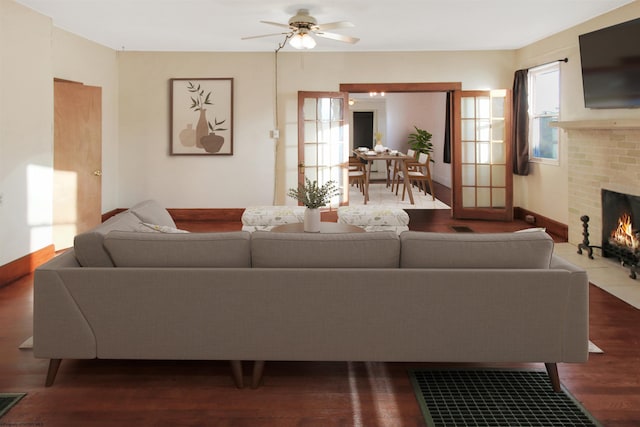 living room with ceiling fan, a fireplace, and dark wood-type flooring