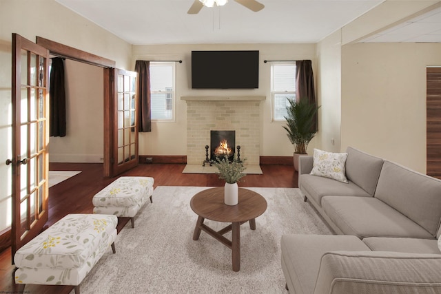 living room with ceiling fan, french doors, wood-type flooring, and a brick fireplace