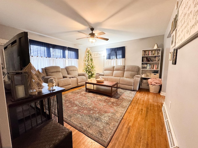 living room featuring ceiling fan, wood-type flooring, and a baseboard heating unit