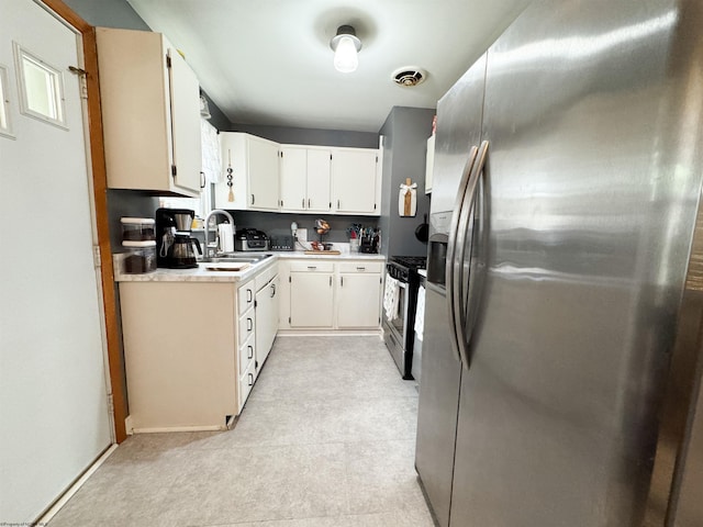 kitchen with appliances with stainless steel finishes, white cabinetry, and sink