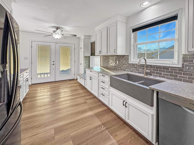 kitchen featuring black fridge, sink, white cabinets, and stainless steel dishwasher