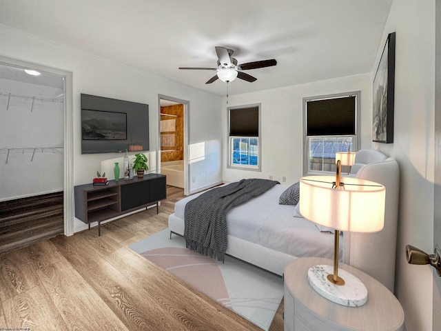 bedroom with ensuite bath, ceiling fan, a spacious closet, light hardwood / wood-style floors, and a closet