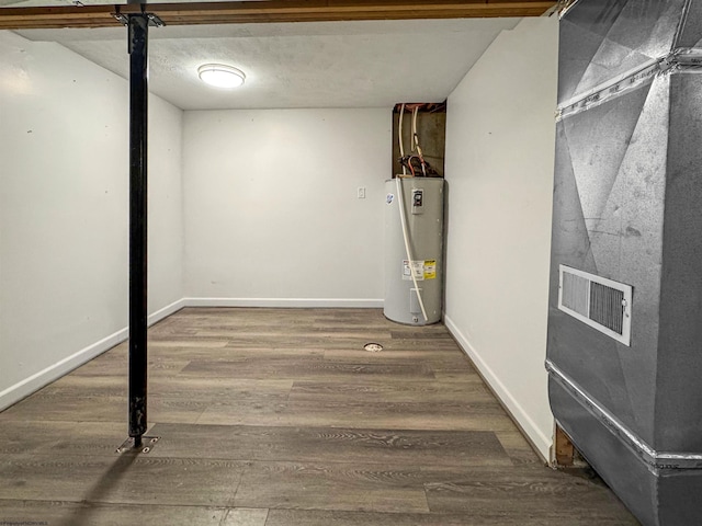 basement with hardwood / wood-style flooring and electric water heater