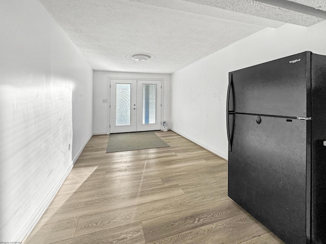 entrance foyer featuring light wood-type flooring, a textured ceiling, and french doors