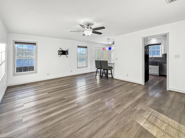 unfurnished living room with dark hardwood / wood-style floors, a healthy amount of sunlight, sink, and ceiling fan