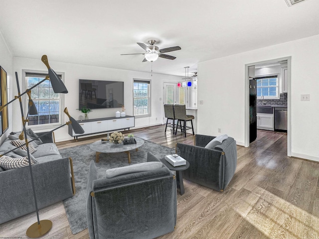 living room featuring ceiling fan, plenty of natural light, wood-type flooring, and sink