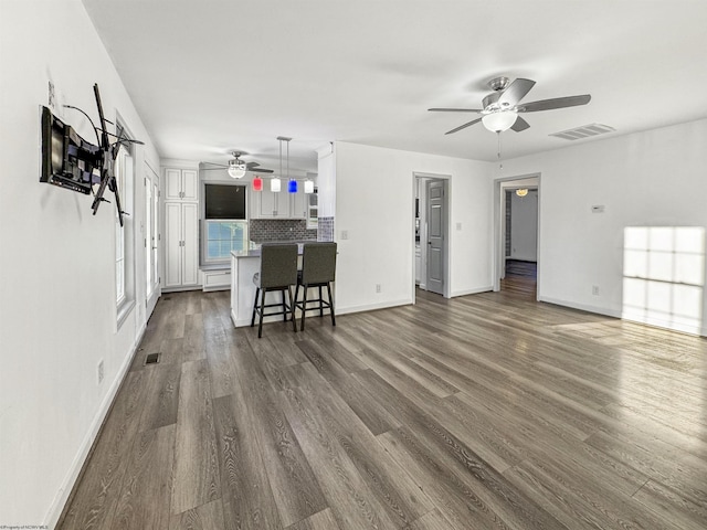 unfurnished living room with ceiling fan and dark hardwood / wood-style flooring