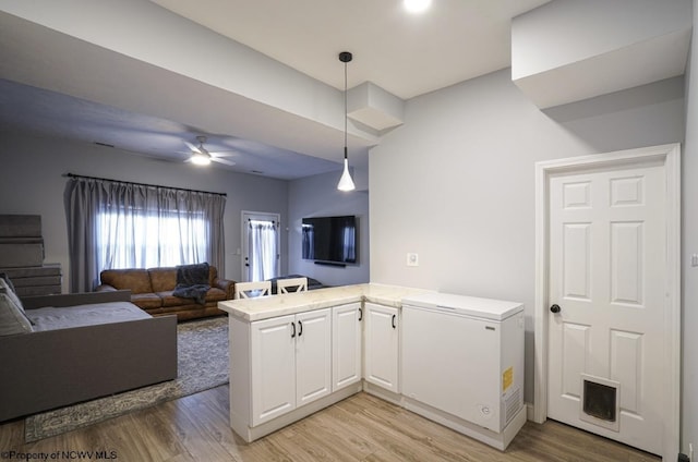 kitchen with kitchen peninsula, light hardwood / wood-style flooring, white cabinetry, and fridge