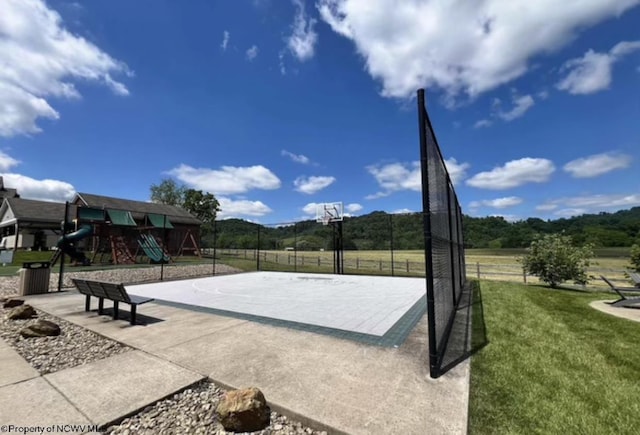 view of sport court featuring a playground, a yard, and a rural view