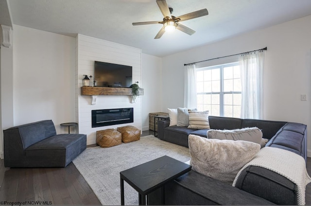 living room featuring a large fireplace, ceiling fan, and dark hardwood / wood-style flooring