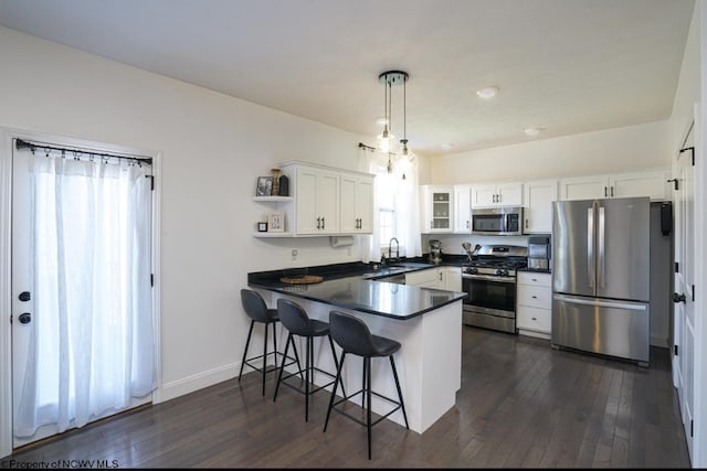 kitchen with sink, hanging light fixtures, dark hardwood / wood-style floors, white cabinetry, and stainless steel appliances