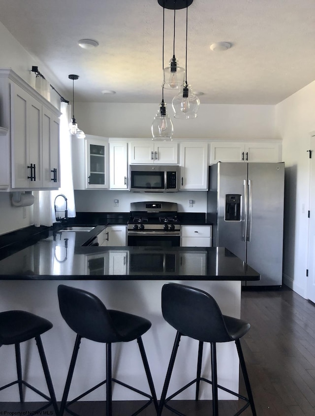 kitchen featuring pendant lighting, white cabinets, a kitchen breakfast bar, dark hardwood / wood-style floors, and stainless steel appliances