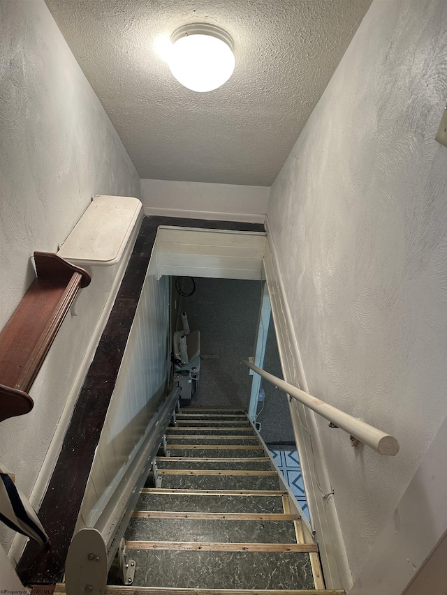 stairway featuring a textured ceiling