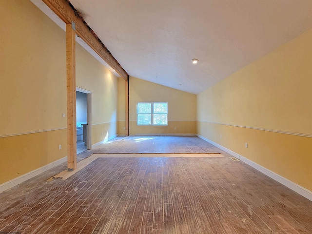 spare room with hardwood / wood-style floors and vaulted ceiling