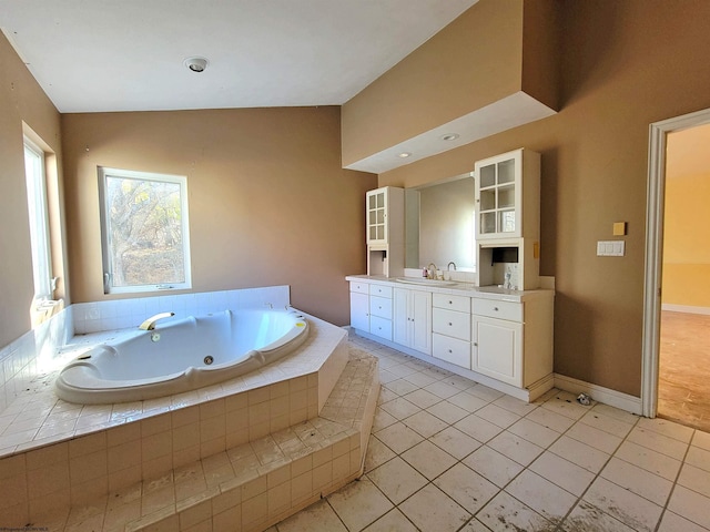 bathroom featuring tile patterned floors, vanity, tiled bath, and vaulted ceiling