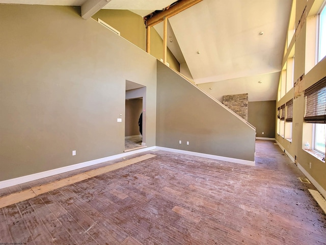 unfurnished living room with beamed ceiling, wood-type flooring, and high vaulted ceiling