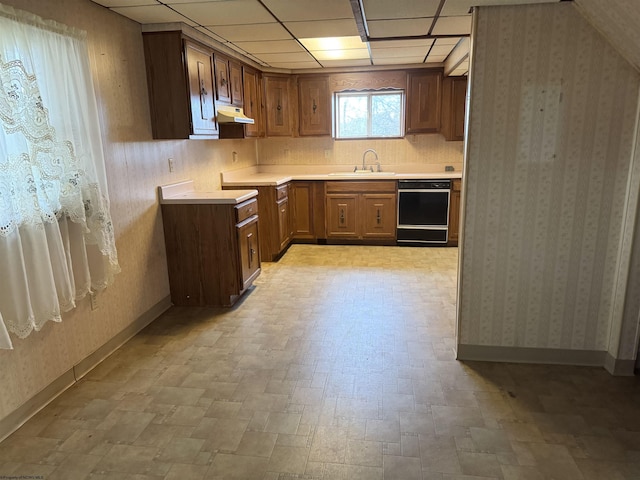 kitchen with a paneled ceiling, dishwasher, and sink