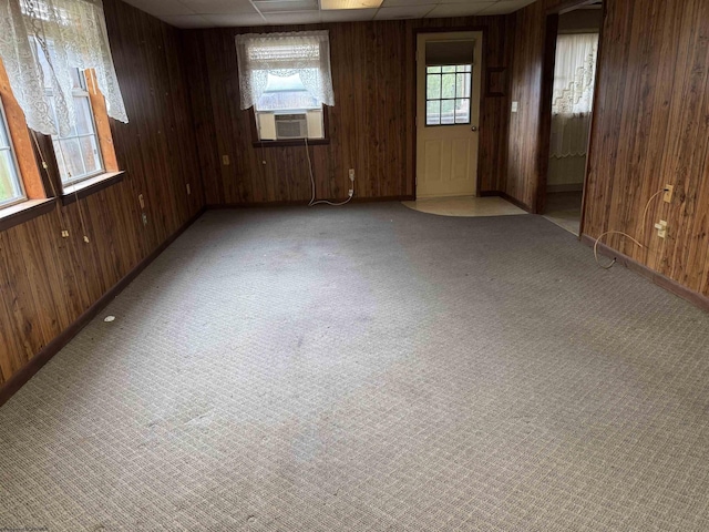 carpeted empty room featuring cooling unit and wood walls