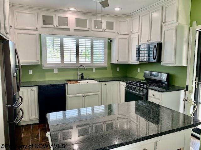 kitchen featuring dark stone counters, black appliances, white cabinets, sink, and ceiling fan