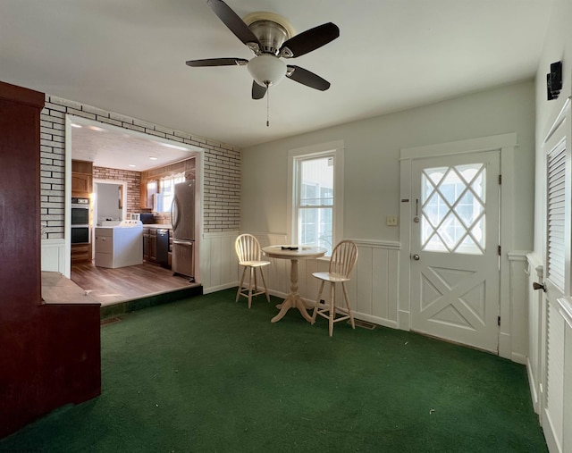 entryway with dark carpet, a healthy amount of sunlight, and brick wall